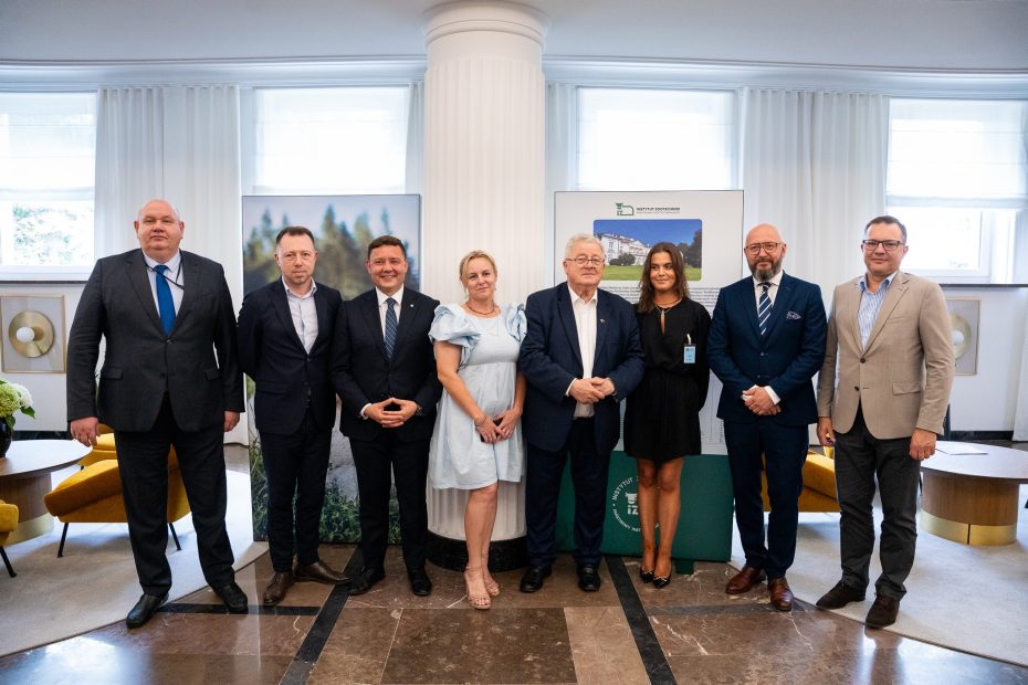 Grupa uczestników uroczystego otwarcia wystawy „Rasy rodzime zwierząt gospodarskich” w Ministerstwie Rolnictwa i Rozwoju Wsi, stojących na tle plansz wystawowych i logotypu Instytutu Zootechniki PIB.