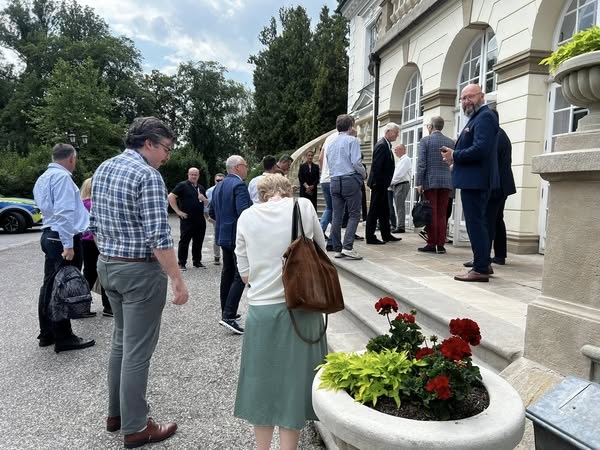 Uczestnicy spotkania zgromadzeni przed wejściem do zabytkowego budynku