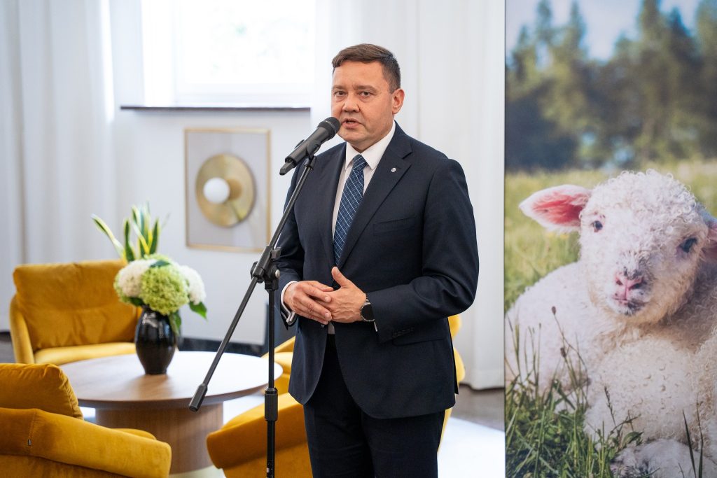 Mężczyzna w garniturze przemawiający podczas otwarcia wystawy rodzimych ras zwierząt gospodarskich.