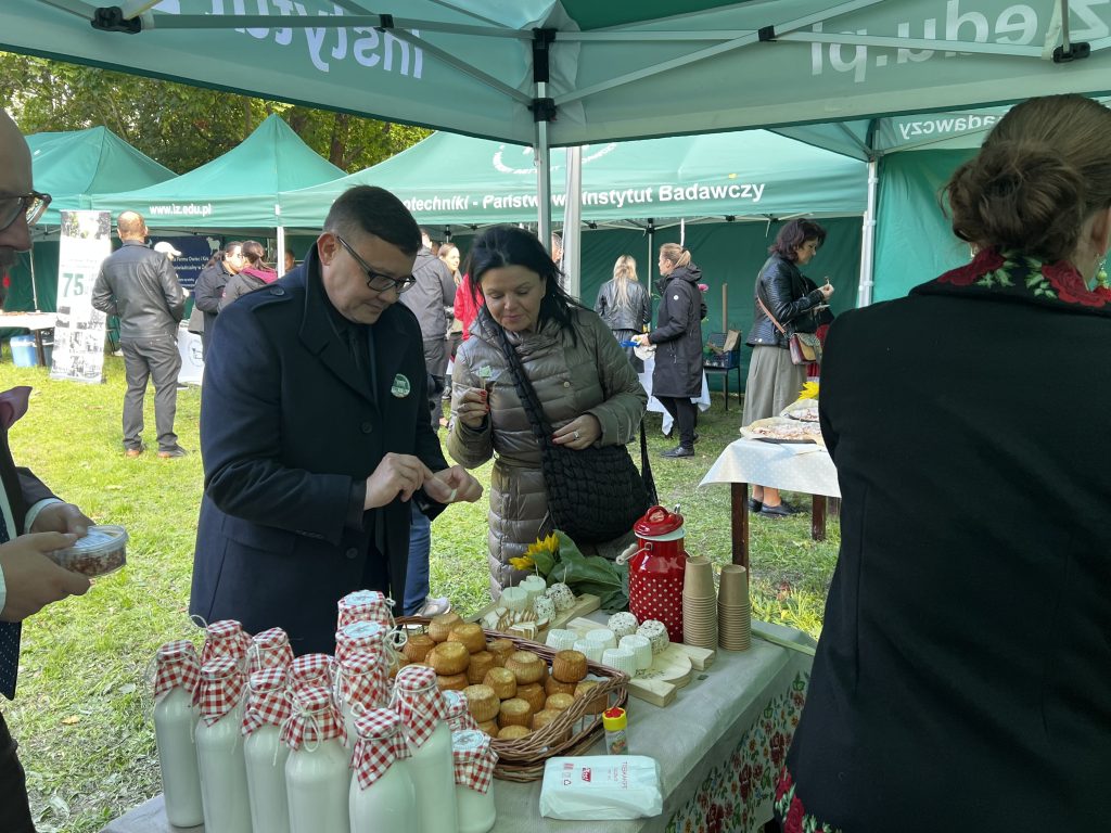Uczestnicy degustują sery przy stoisku Instytutu Zootechniki podczas plenerowego wydarzenia.