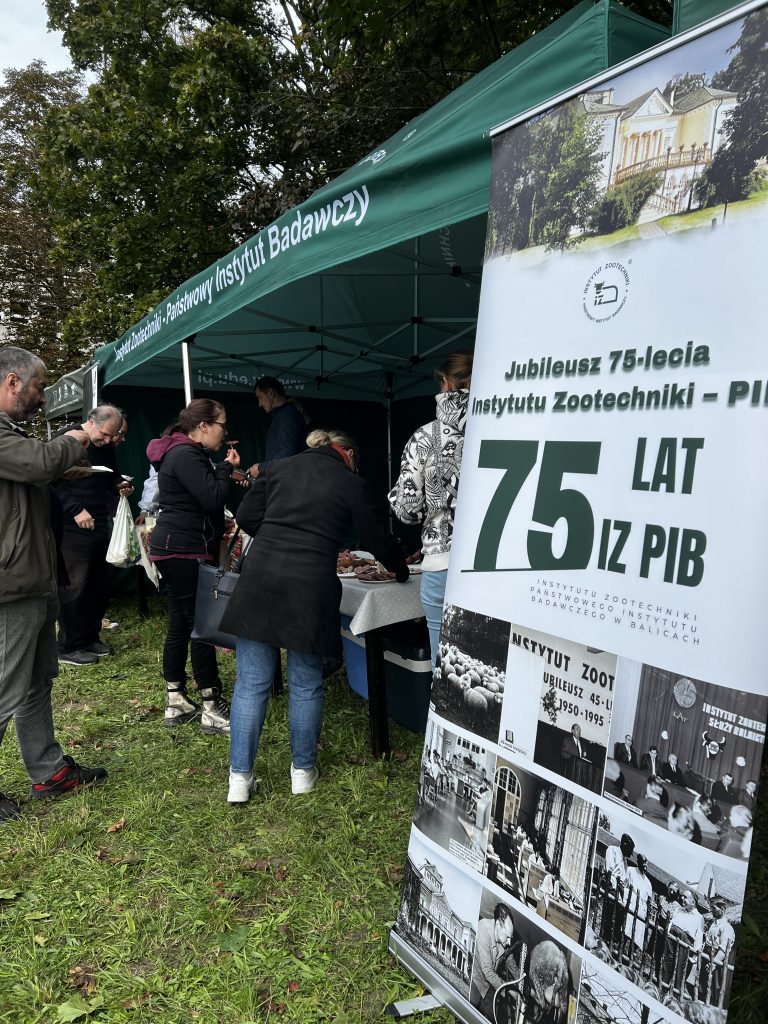 Odwiedzający oglądają stoiska Instytutu Zootechniki PIB, przy jednym z namiotów stoi baner informujący o 75-leciu instytutu.