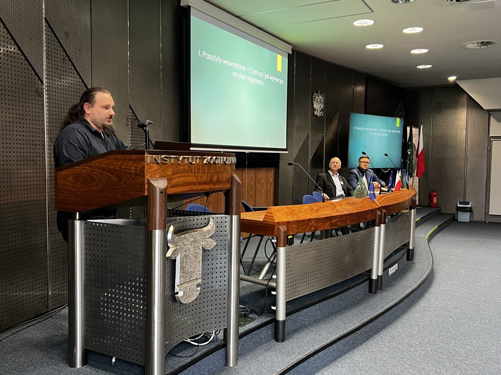 Mężczyzna wygłasza referat o pasożytach wewnętrznych u kóz podczas konferencji w Instytucie Zootechniki.