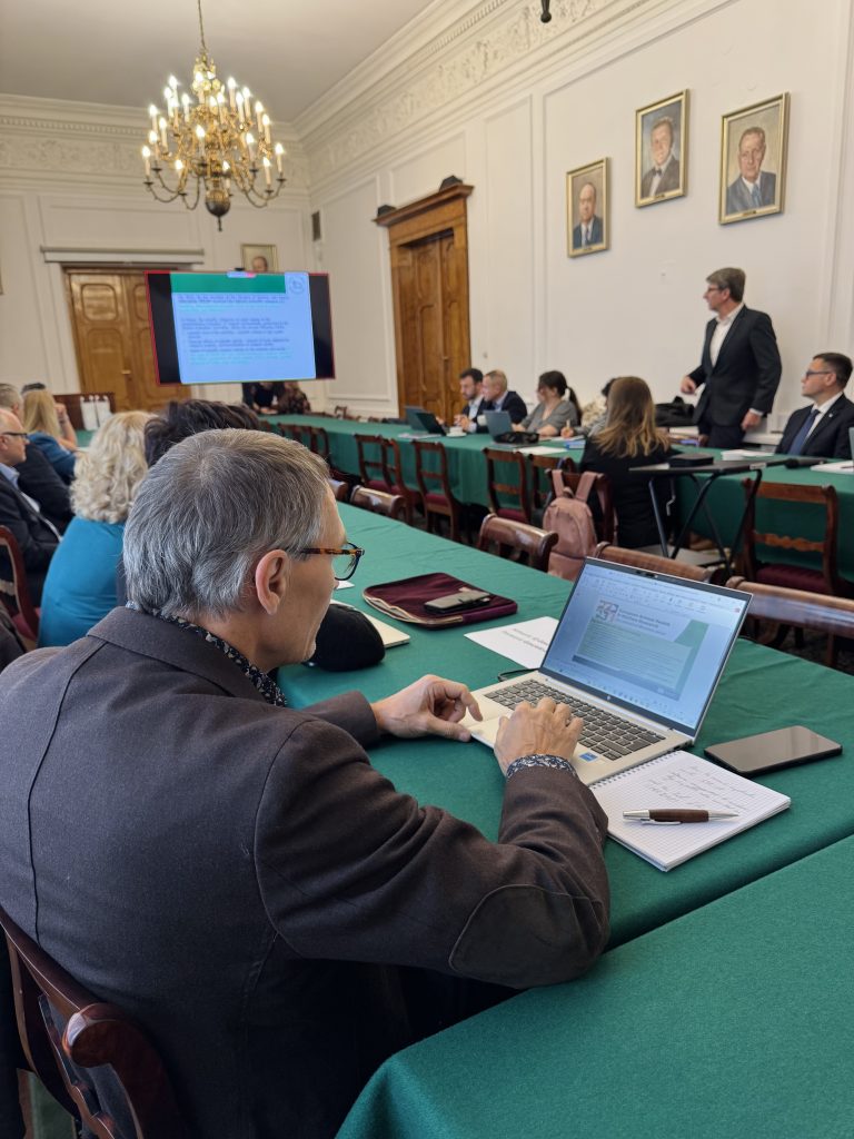 Mężczyzna przy laptopie, w tle prezentacja na ekranie.